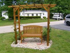 a wooden bench sitting on top of a lush green field next to a park area