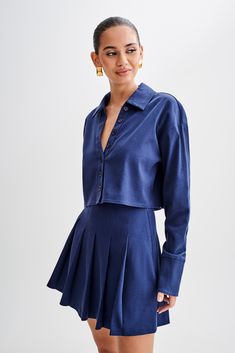 Buttoned and ready. Introducing the JULIANNA Cotton Button Up Shirt in Navy, a versatile staple for every wardrobe. With its collared neckline and functional center front placket with button closure, this shirt exudes timeless sophistication. The cropped length adds a modern twist, while long sleeves and functional cuffs offer both style and practicality. Crafted from breathable, unlined cotton, it ensures comfort all day long. Complete with a back inverted box pleat and back yoke details, this shirt combines classic elements with contemporary flair. Whether dressed up the Julianna Cotton Pleated Mini Skirt or dressed down with jeans, the Julianna Cotton Button Up Shirt is a versatile piece that effortlessly elevates any outfit.