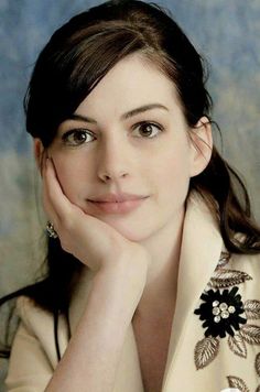 a woman with her hand on her chin and looking at the camera while posing for a photo