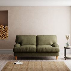 a green couch sitting on top of a hard wood floor next to a wooden table