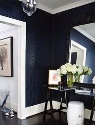 a black and white room with flowers in vases on the table next to a mirror