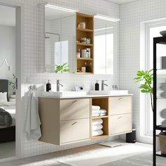 a bathroom with two sinks, mirrors and towels on the shelf in front of it