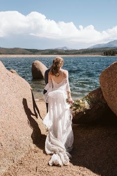 a bride and groom walking by the water