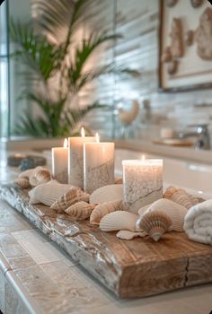 candles and seashells sit on a wooden tray in the middle of a bathroom