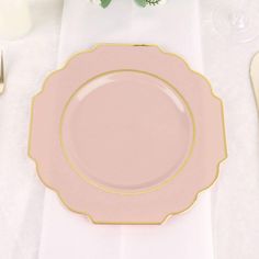 a pink plate sitting on top of a table next to utensils and flowers