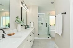 a white bathroom with two sinks and a shower