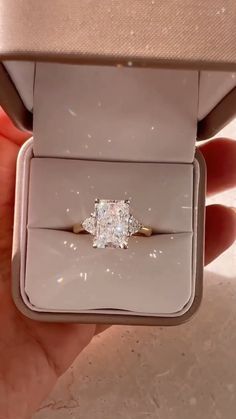 a person is holding an engagement ring in their hand and it's inside the box