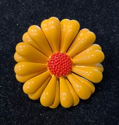 a yellow flower with red center sitting on a black surface