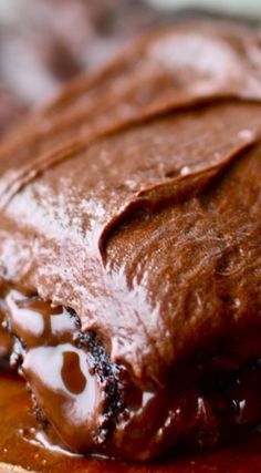 a close up of a piece of chocolate cake on a wooden board with icing