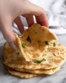 a hand is picking up a cracker from a stack of flatbreads on a marble surface