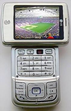 an open cell phone sitting on top of another cell phone with a soccer game on it's screen