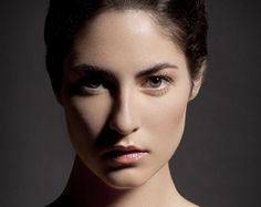 a woman is posing for a photo with her hair up in a bun and makeup