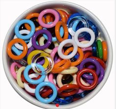 a white bowl filled with lots of different colored plastic rings on top of each other