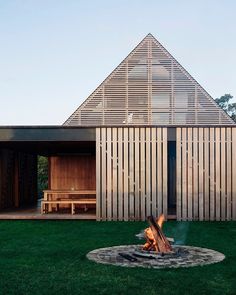 an outdoor fire pit in front of a house with wooden slats on the roof