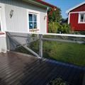 a red house with a white fence in front of it and grass on the other side