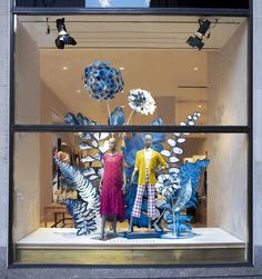 two mannequins are standing in front of a window with blue and white decorations