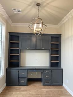 an empty room with built in cabinets and a chandelier