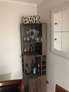 a bar with liquor bottles and glasses on the top shelf, next to a mirror