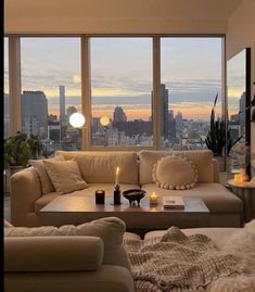 a living room filled with furniture and large windows overlooking the cityscape at sunset