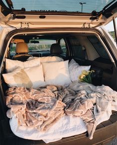 the back end of a car with blankets and pillows in it's trunk area