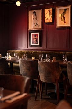 an empty restaurant with red walls and wooden tables set up for two people to eat