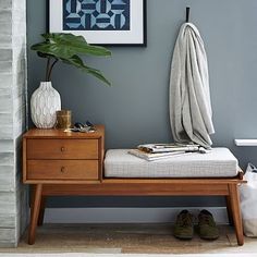 a wooden bench sitting next to a white vase