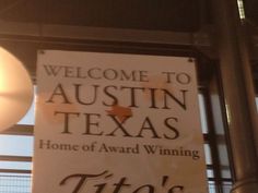 a sign hanging from the side of a building that says, welcome to austin texas home of award winning titto's