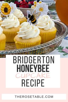 some cupcakes with white frosting and honeybee decorations are on a plate