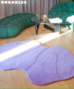 a living room with green couches and purple rugs on the wooden flooring