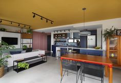 a living room filled with furniture and a flat screen tv mounted to the wall next to a kitchen