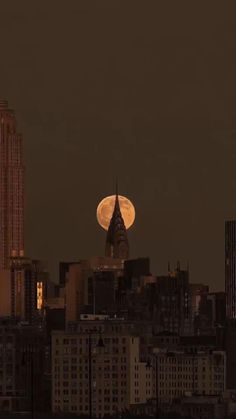 the full moon is seen over a city skyline