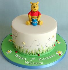 a winnie the pooh birthday cake with grass and flowers