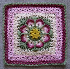 a crocheted square with a flower in the center on a gray surface,