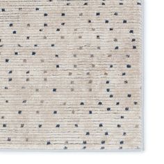 a beige rug with black dots on the top and bottom, against a white background