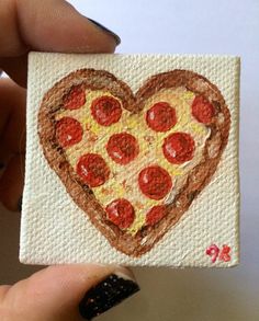 someone is holding up a piece of art that looks like a heart shaped pizza slice