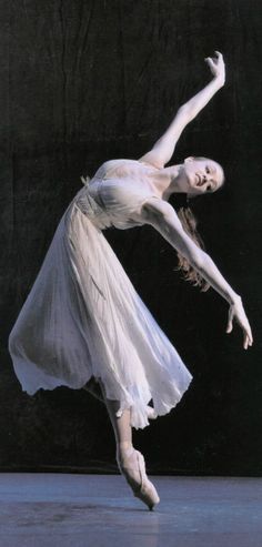 a ballerina in white is performing on stage