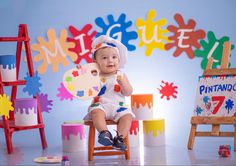 a baby sitting in a chair with paint on it