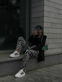 a woman sitting on the side of a building while holding a cell phone to her ear