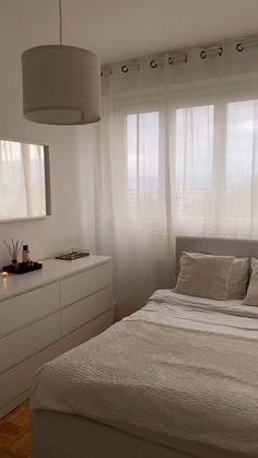 a bedroom with white furniture and large windows