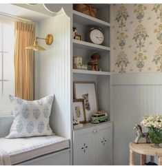 a window seat in a room with flowers on the wall and a clock above it