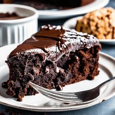 a piece of chocolate cake on a white plate with a fork next to the slice