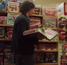 two people standing in front of a store display filled with books and magazines, one holding a box