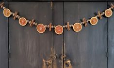 an orange slice garland is hanging on a wooden door with cinnamon sticks and other decorations