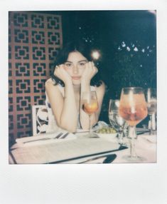 a woman sitting at a table with two wine glasses