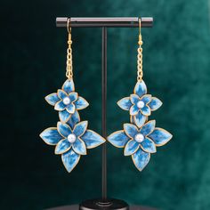 These hand-painted flowers, inspired by the iconic Mardi Gras float flowers, will bring a little bit of New Orleans style to your ears! Based on the Henri Clematis flower, this pair sparkles in rich blues and gold and white pearl centers add an extra dash of elegance.  Dimensions: 3.875in x 1.75in Each flower is carefully shaped out of paper and painted before being coated in a durable clear acrylic, creating pieces that are bright and bold while being incredibly lightweight and wearable. Proudl Handmade Enamel Flower Shaped Earrings, Unique Hand Painted Flower Drop Earrings, Handmade Enamel Drop Flower Earrings, Elegant Hand Painted Drop Flower Earrings, Artistic Hand Painted Flower Earrings, Blue Flower-shaped Hand Painted Earrings, Blue Hand Painted Flower Earrings, Mardi Gras Float, New Orleans Style