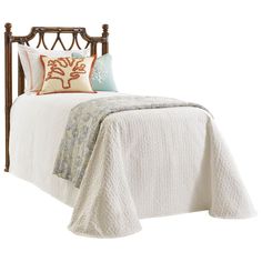 a bed with a white bedspread and two pillows on top of the headboard