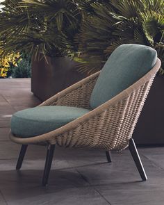 a wicker chair sitting on top of a tiled floor next to a potted plant