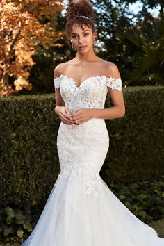 a woman in a wedding dress posing for the camera with her hand on her hip