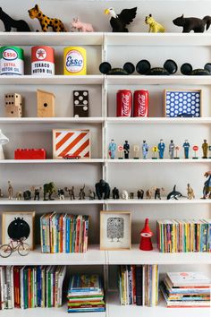 shelves filled with toys and books on top of each other in front of a white wall