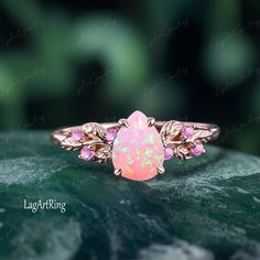 a pink opalite ring sitting on top of a green leaf